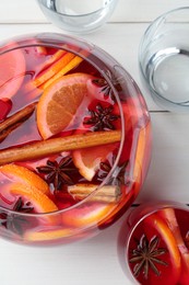 Photo of Bowl of delicious aromatic punch drink and glasses on white wooden table, flat lay