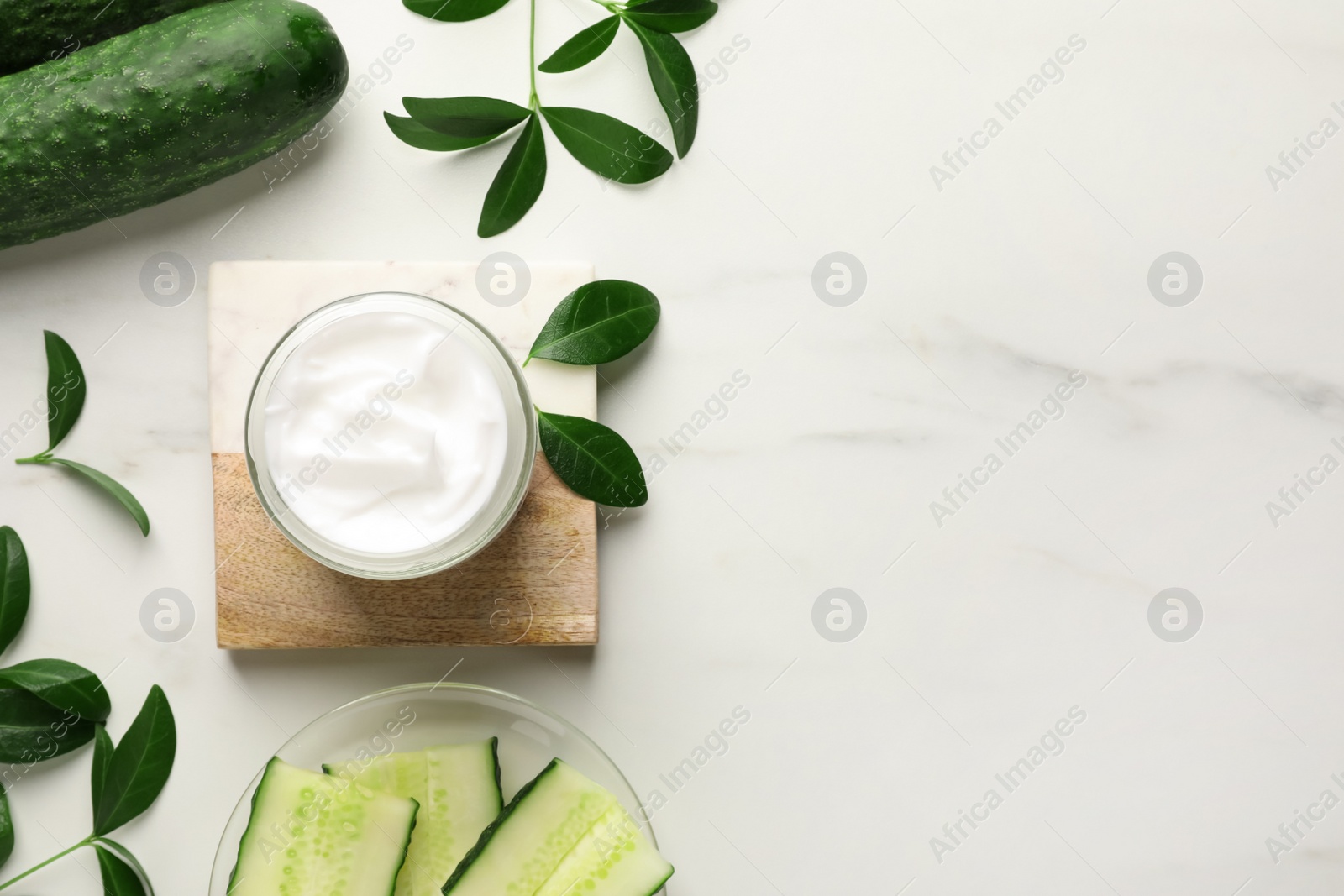 Photo of Glass jar of cucumber face cream on white marble table, flat lay. Space for text