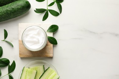 Glass jar of cucumber face cream on white marble table, flat lay. Space for text