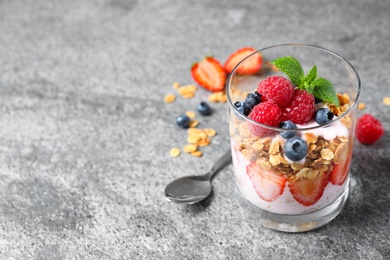 Photo of Glass of tasty homemade granola dessert on grey table, space for text. Healthy breakfast