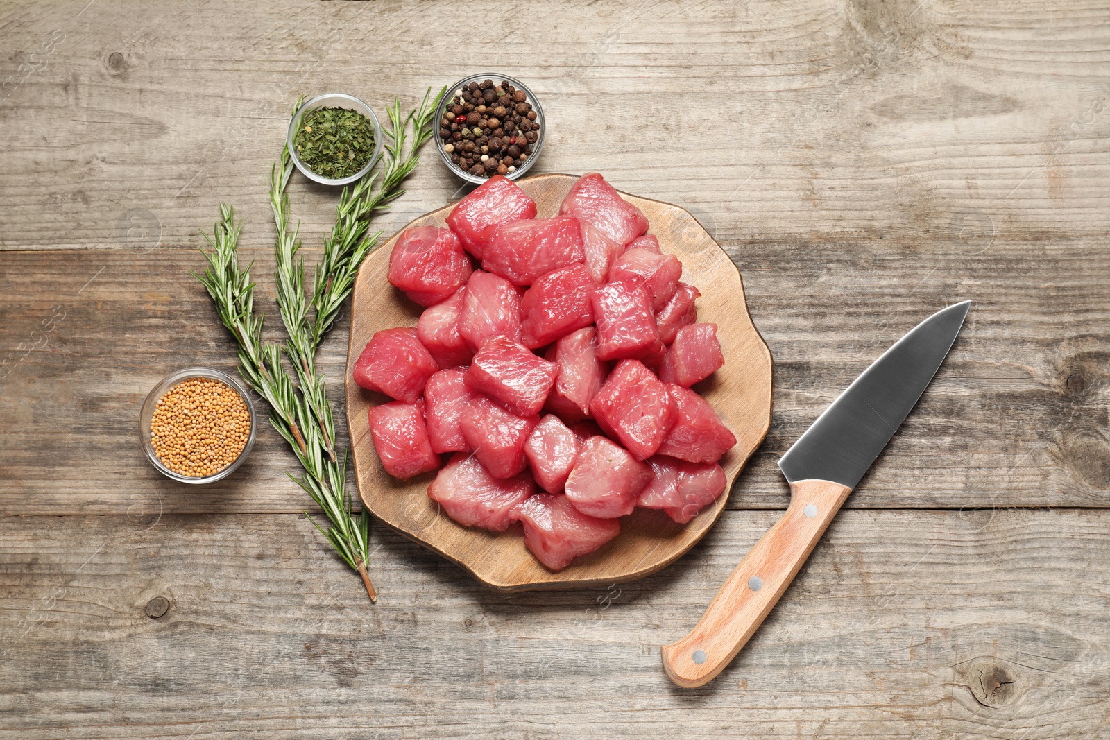 Photo of Cooking delicious goulash. Raw beef meat, knife and different spices on wooden table, flat lay