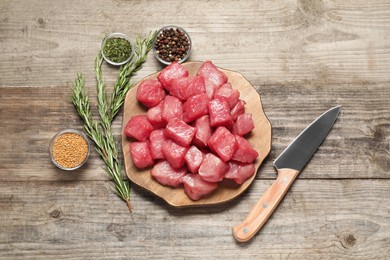 Photo of Cooking delicious goulash. Raw beef meat, knife and different spices on wooden table, flat lay