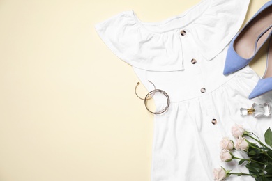 Photo of Flat lay composition with stylish dress and flowers on beige background. Space for text