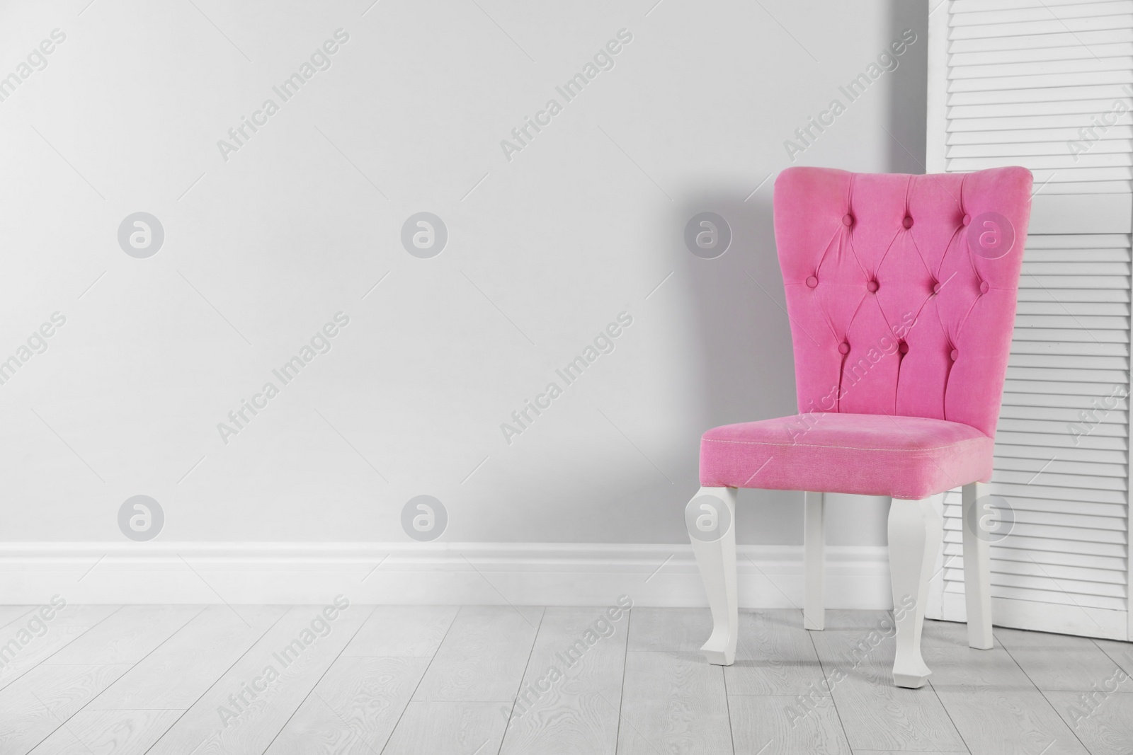 Photo of Stylish pink chair and folding screen near white wall. Space for text