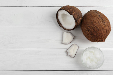 Flat lay composition with coconut oil on white wooden table, space for text. Cooking ingredients