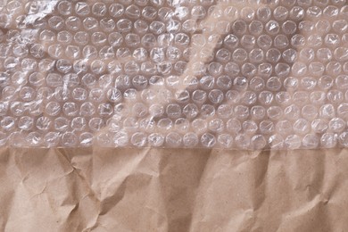 Photo of Transparent bubble wrap on kraft paper, top view. Space for text