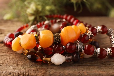 Beautiful bracelets with gemstones on wooden surface, closeup