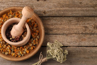 Mortar with pestle, many different dry herbs and flowers on wooden table, flat lay. Space for text