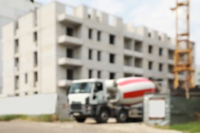 Blurred view of unfinished building and concrete mixer truck outdoors