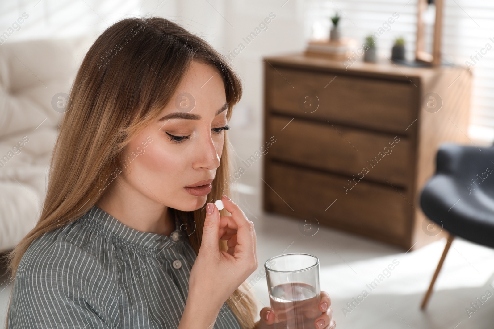 Photo of Young woman taking abortion pill at home