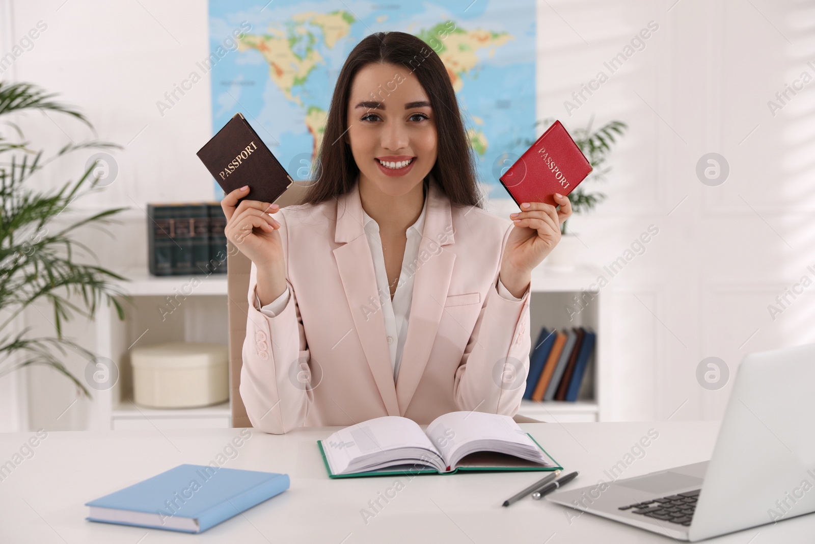 Photo of Happy manager holding passports at desk in travel agency