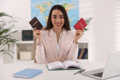 Happy manager holding passports at desk in travel agency