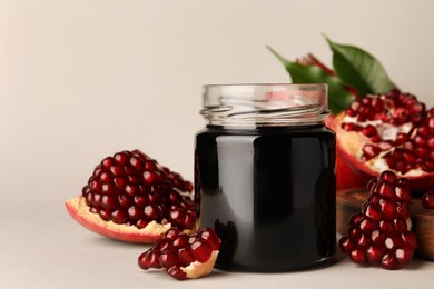 Photo of Glass jar of tasty pomegranate sauce and fresh ripe fruits on white background