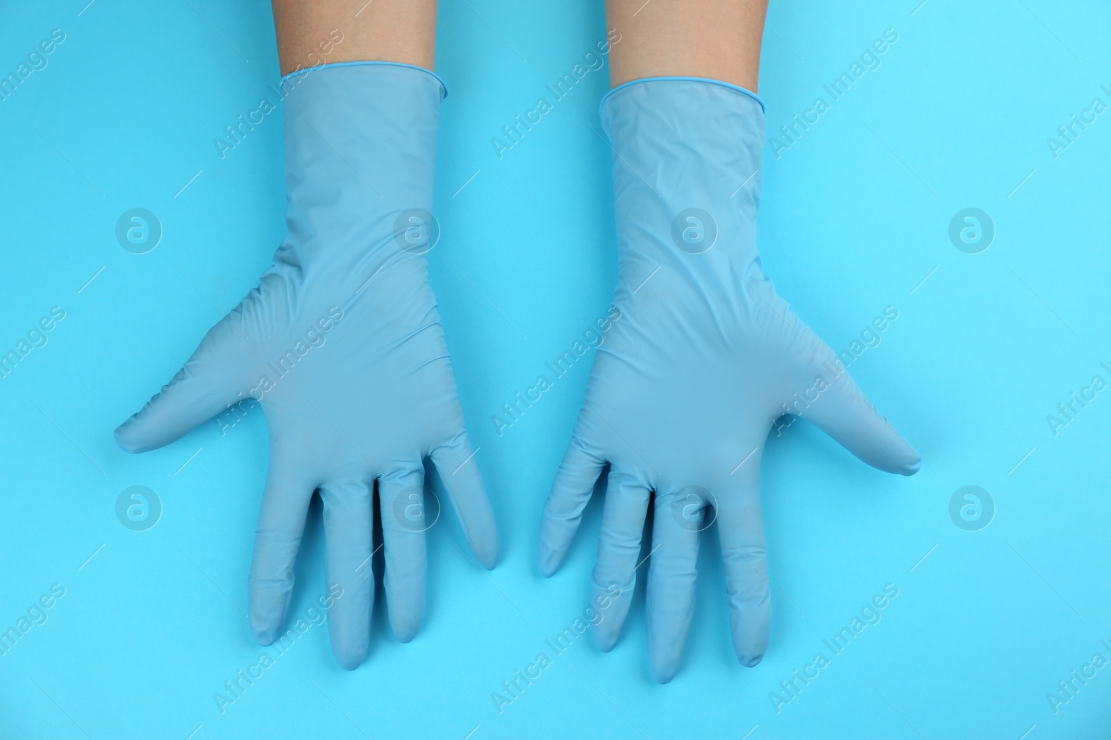 Photo of Person in medical gloves on light blue background, top view