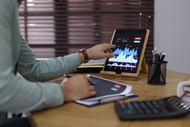 Photo of Businessman working with tablet and chart in office, closeup. Forex trading
