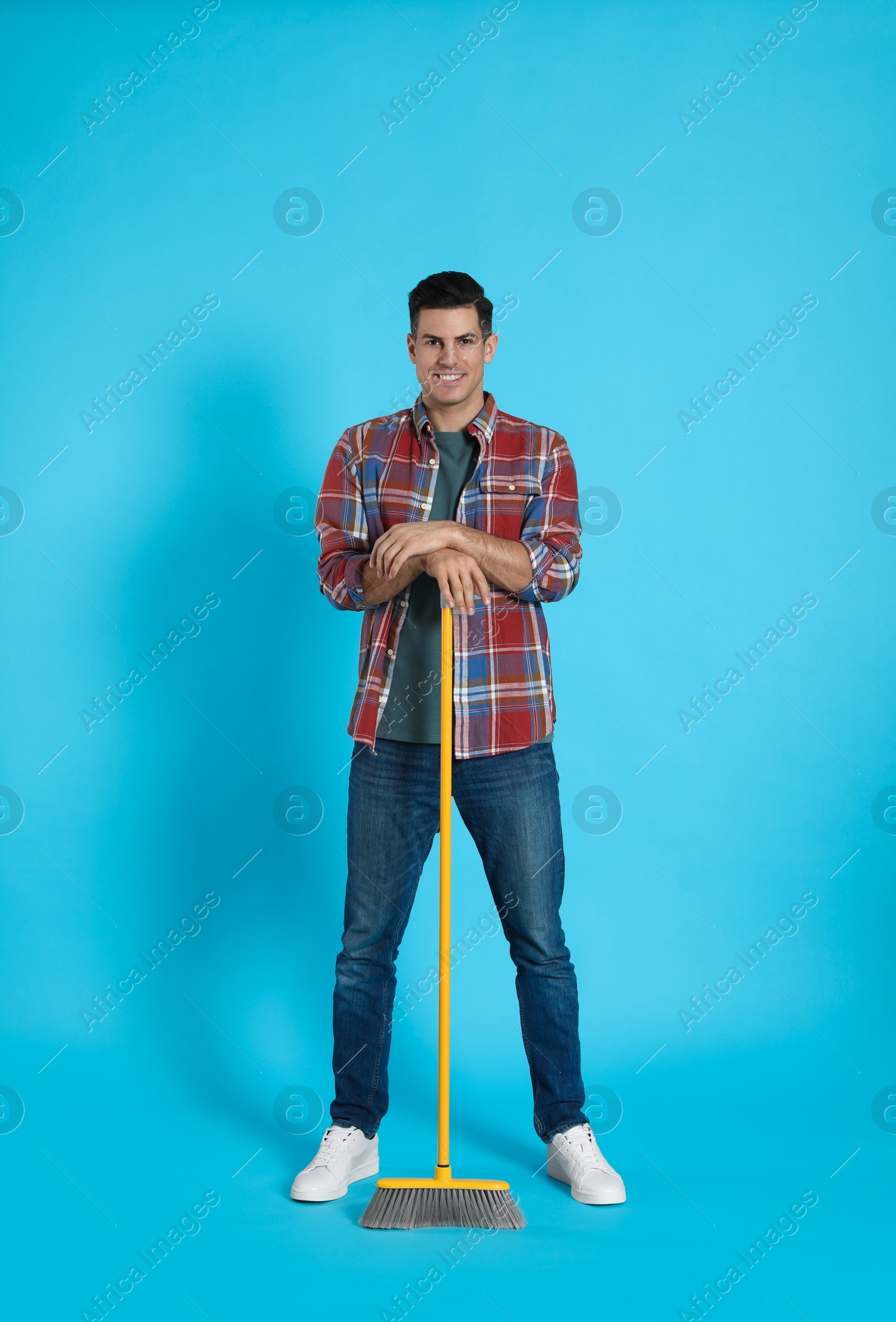 Photo of Man with yellow broom on light blue background