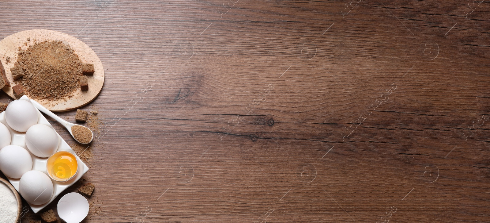 Photo of Fresh breadcrumbs and eggs on wooden table, flat lay. Space for text