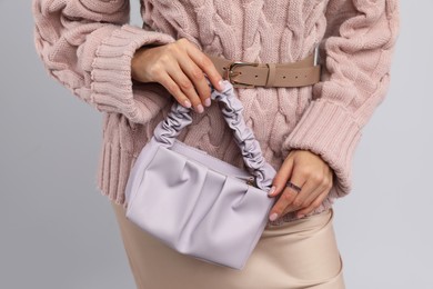 Fashionable woman with stylish bag on light background, closeup