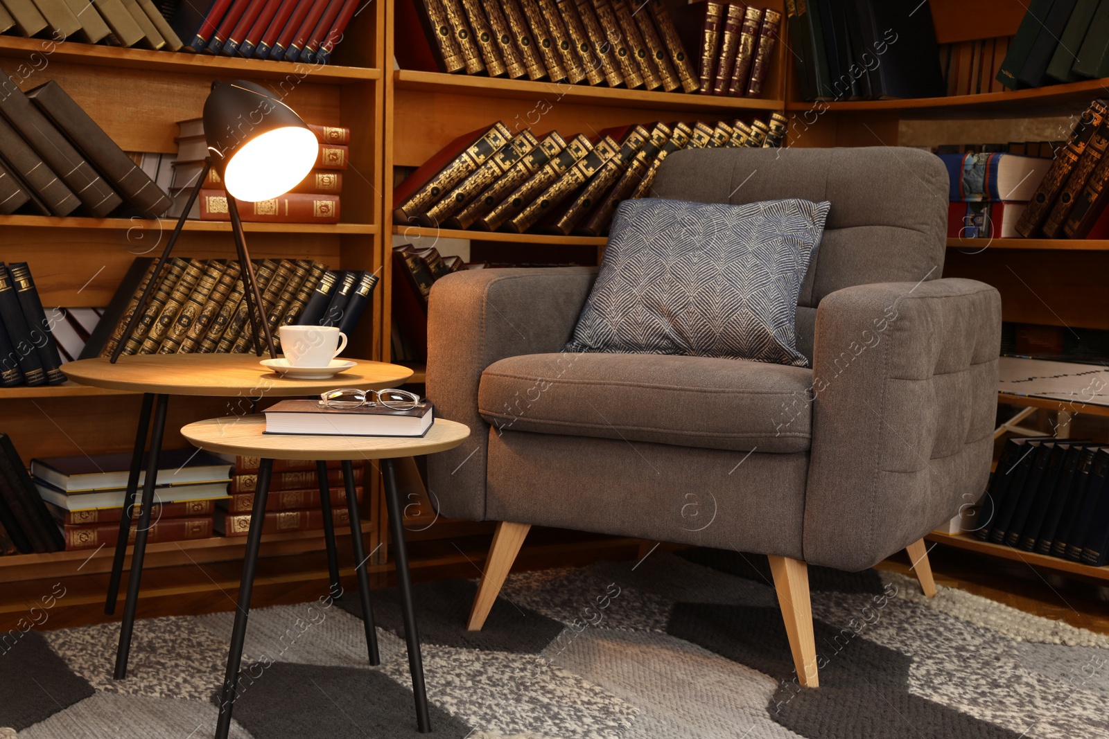 Photo of Cozy home library interior with comfortable armchair and collection of vintage books on shelves