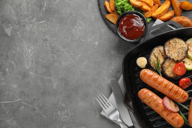 Photo of Delicious grilled sausages and vegetables on grey table, flat lay. Space for text