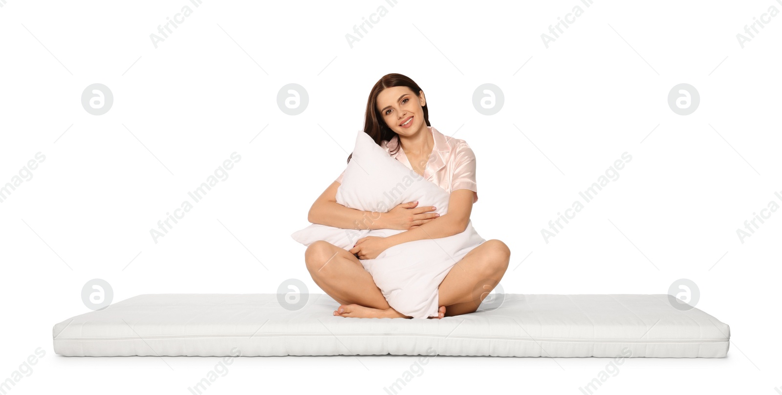 Photo of Young woman on soft mattress holding pillow against white background