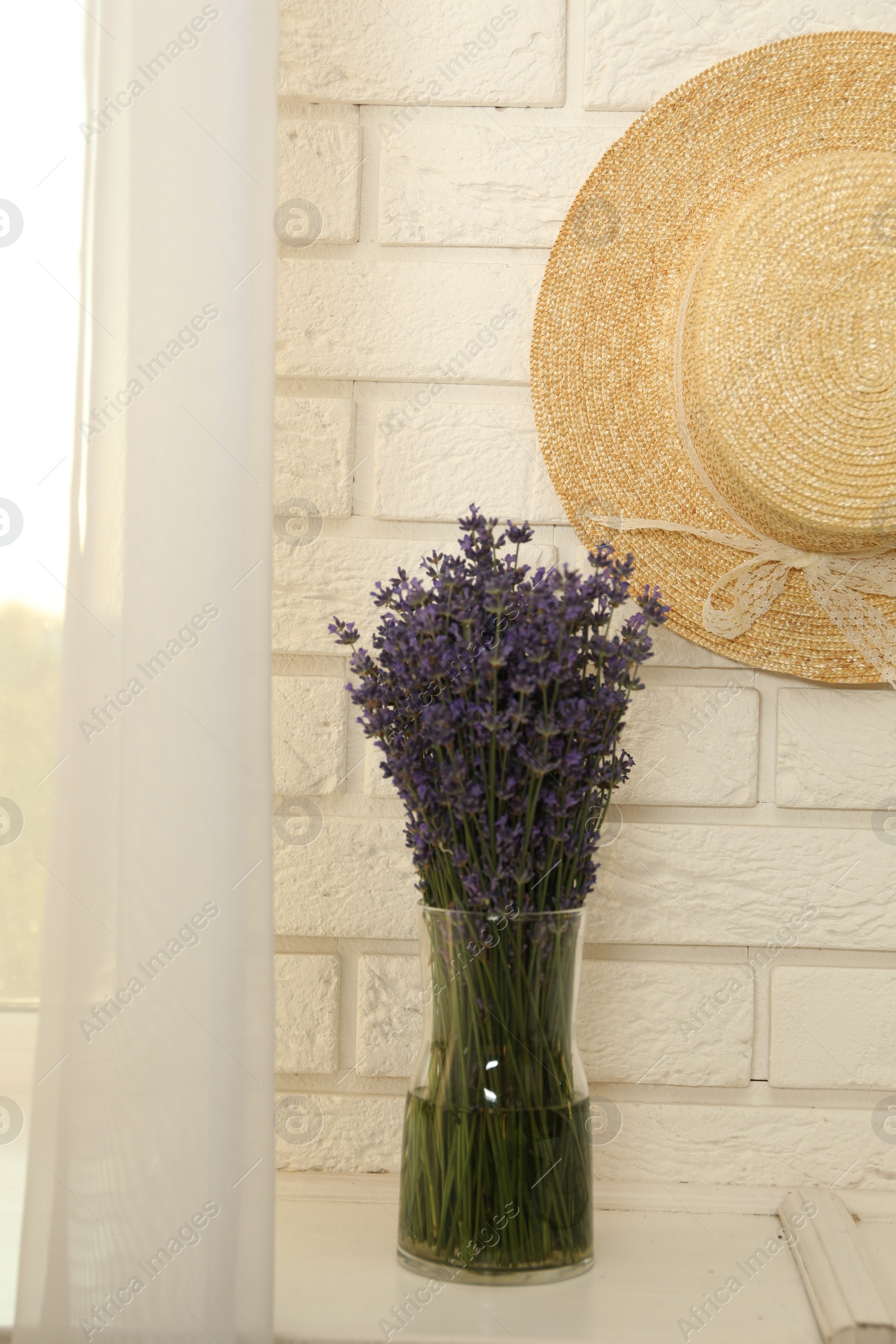 Photo of Beautiful lavender bouquet and straw hat near window indoors