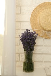 Beautiful lavender bouquet and straw hat near window indoors