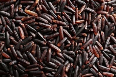 Photo of Raw black rice as background, closeup view