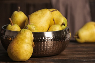 Photo of Fresh ripe pears on wooden table against blurred background