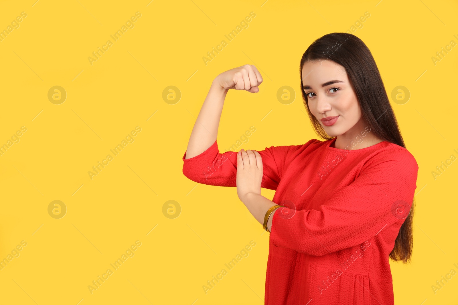 Photo of Strong woman as symbol of girl power on yellow background, space for text. 8 March concept