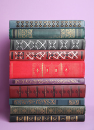 Photo of Stack of different hardcover books on violet background