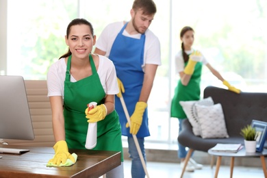 Photo of Team of professional janitors in uniform cleaning office