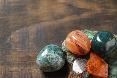 Different beautiful gemstones on textured wooden table