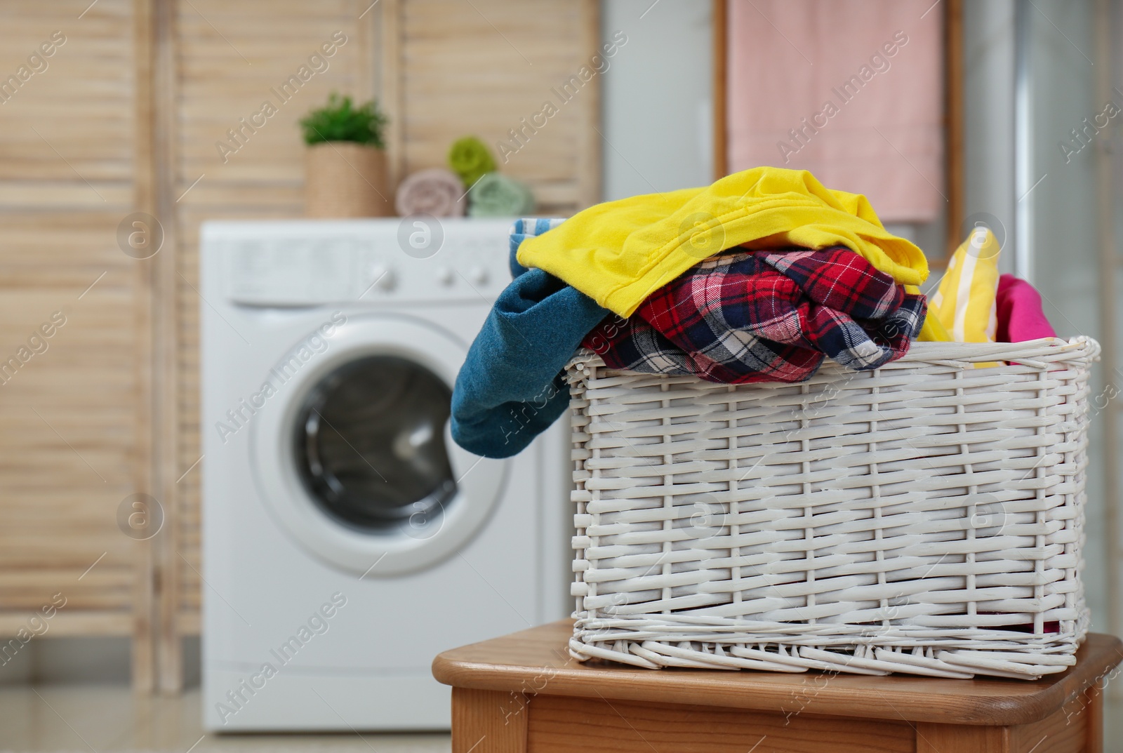 Photo of Wicker basket with laundry in bathroom. Space for text