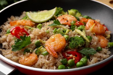 Photo of Tasty rice with shrimps and vegetables in frying pan, closeup