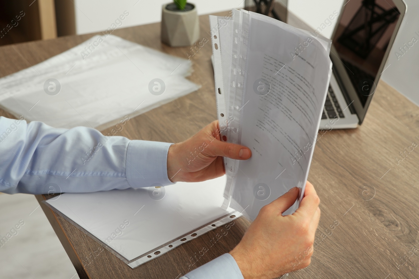 Photo of Businessman working with documents at wooden table in office, closeup