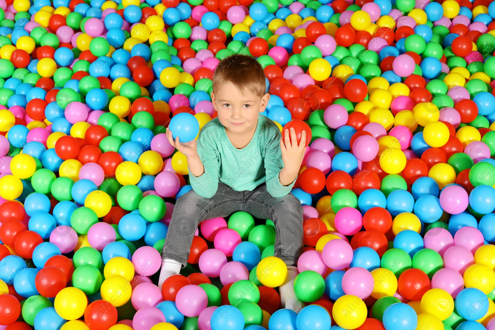 Photo of Cute child playing in ball pit indoors