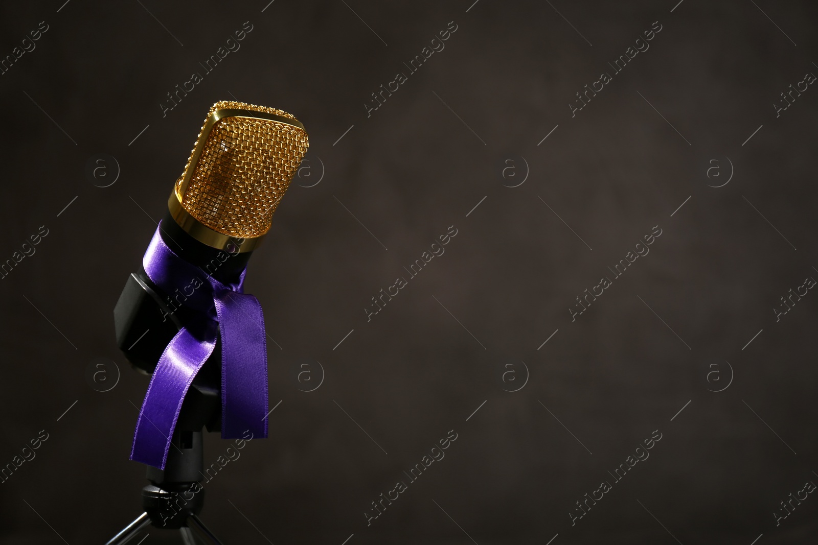 Photo of Microphone with purple awareness ribbon on dark background, space for text