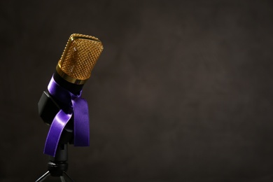 Microphone with purple awareness ribbon on dark background, space for text