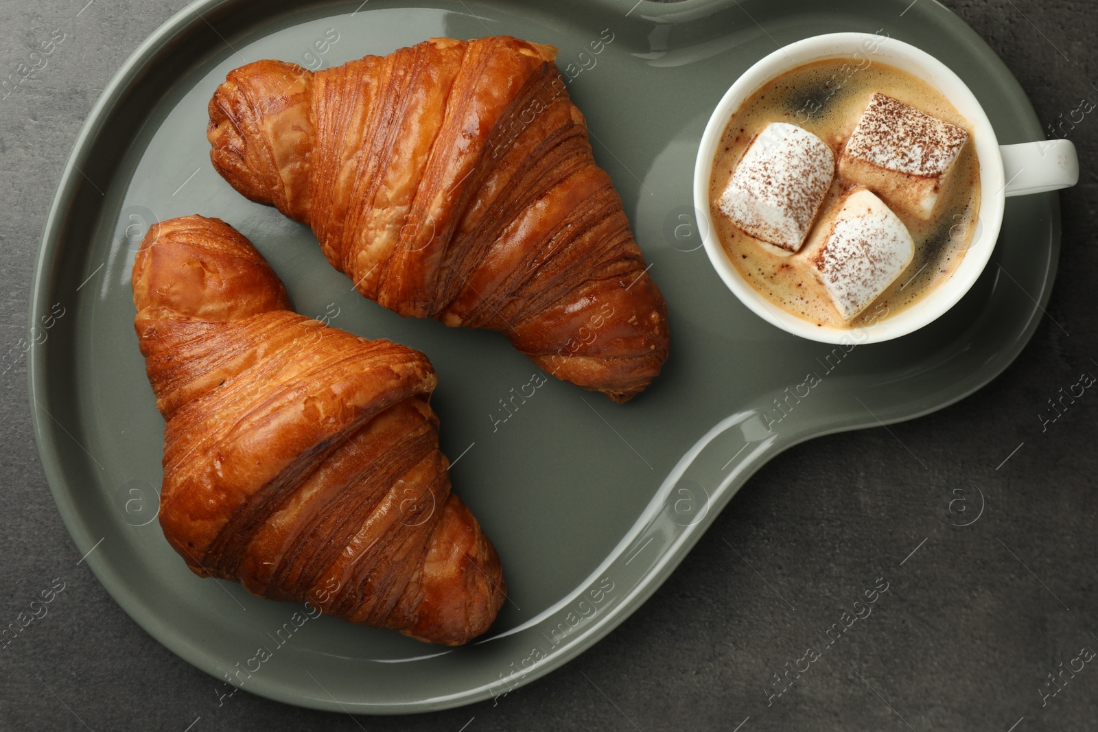 Photo of Tasty croissants served with cup of hot drink on grey textured table, top view