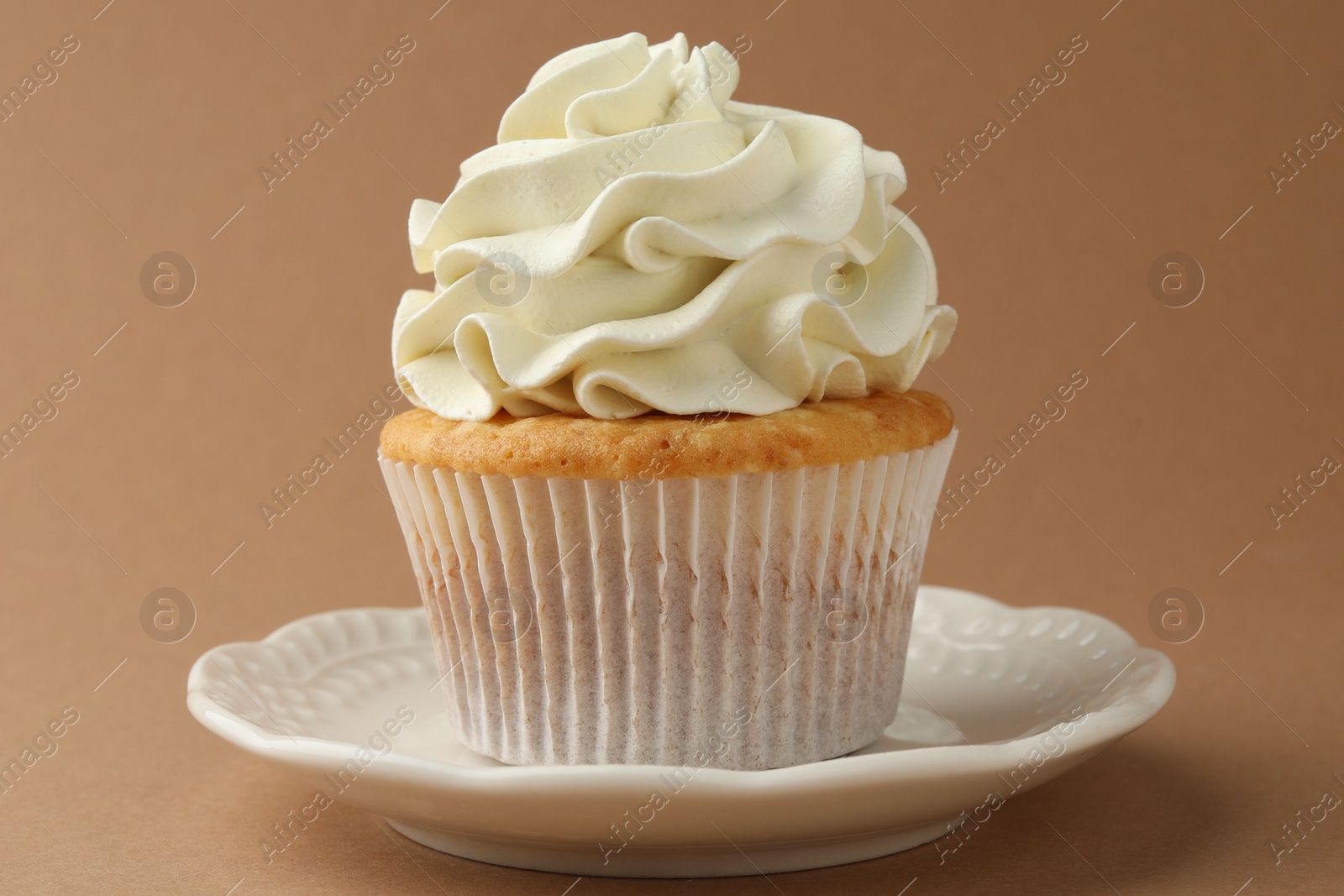 Photo of Tasty vanilla cupcake with cream on dark beige background, closeup