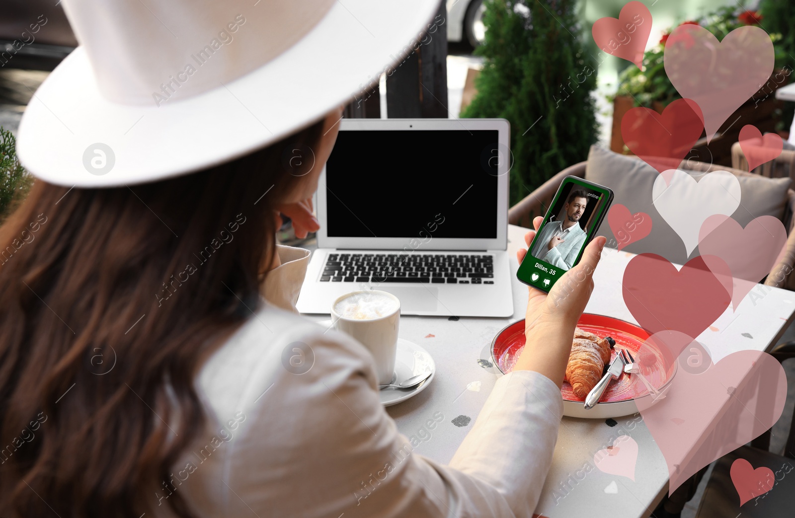 Image of Woman viewing male profile on dating site via mobile phone at cafe