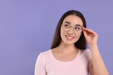 Beautiful woman wearing glasses on violet background, space for text