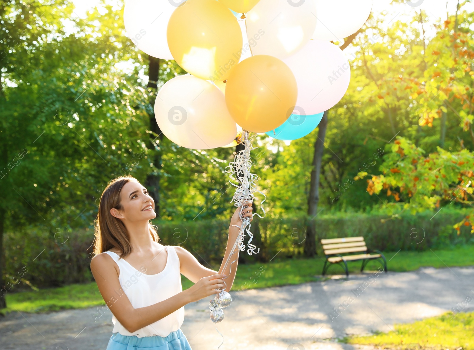 Photo of Beautiful teenage girl holding colorful balloons in park