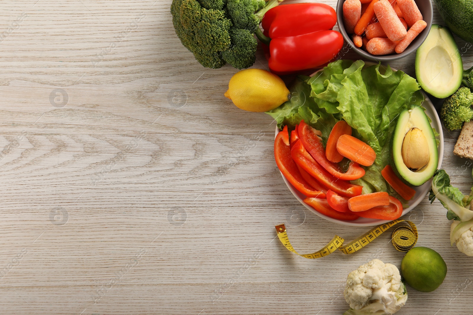 Photo of Healthy diet. Fresh vegetables and measuring tape on light wooden table, flat lay. Space for text