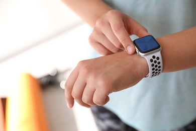 Photo of Woman checking fitness tracker in gym, closeup