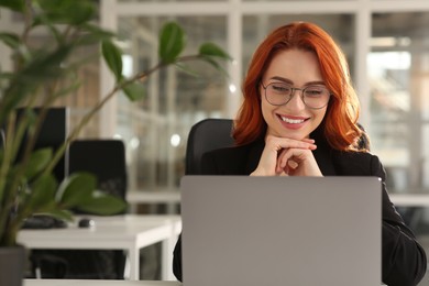Photo of Happy woman working with laptop in office