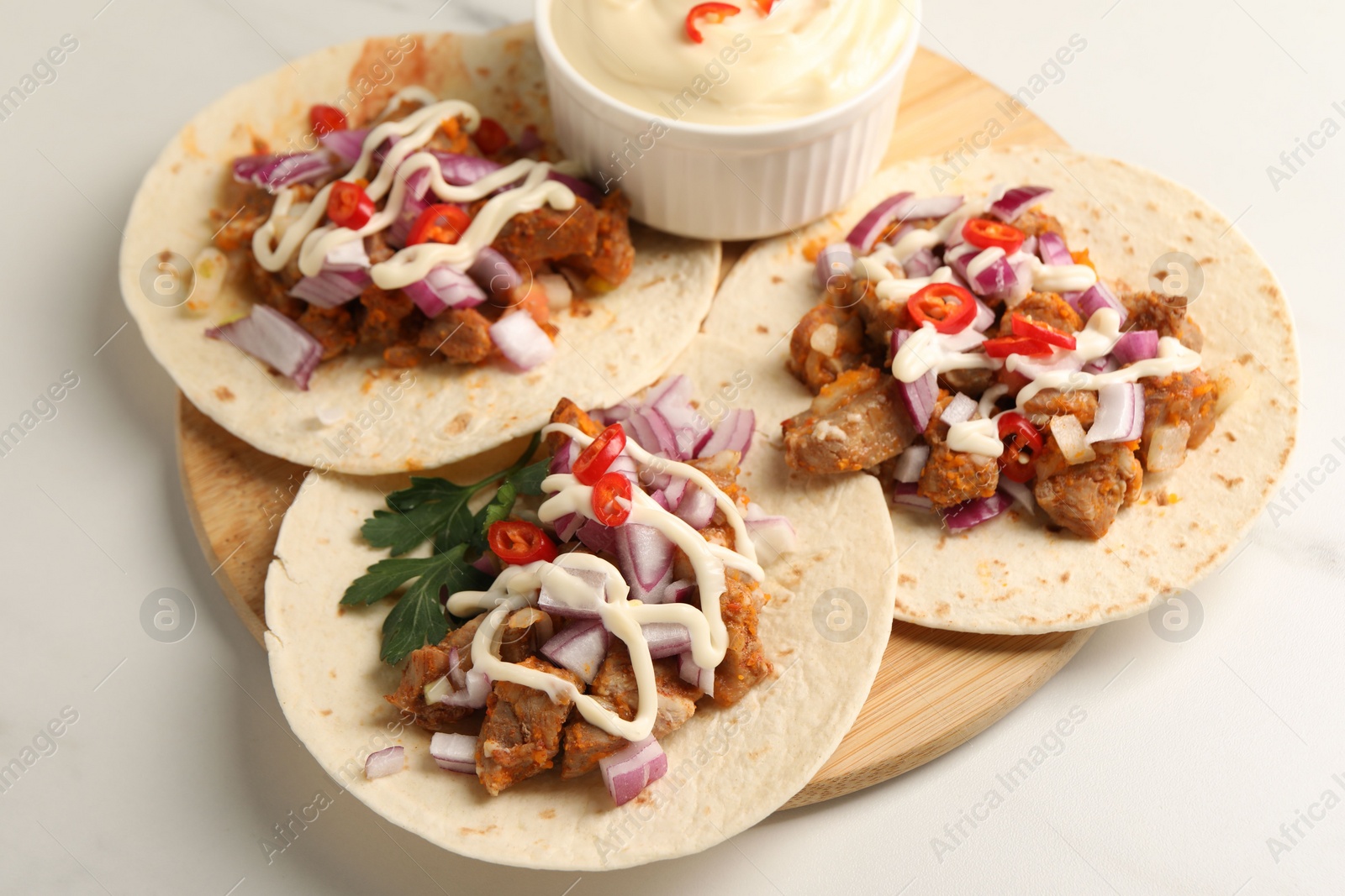 Photo of Delicious tacos with vegetables, meat and sauce on white table