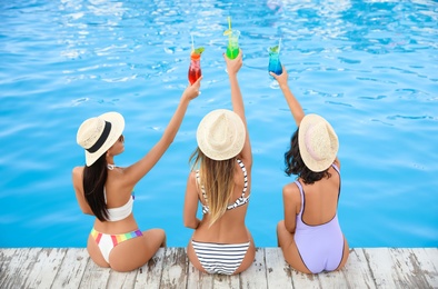 Group of friends with refreshing cocktails near outdoor swimming pool