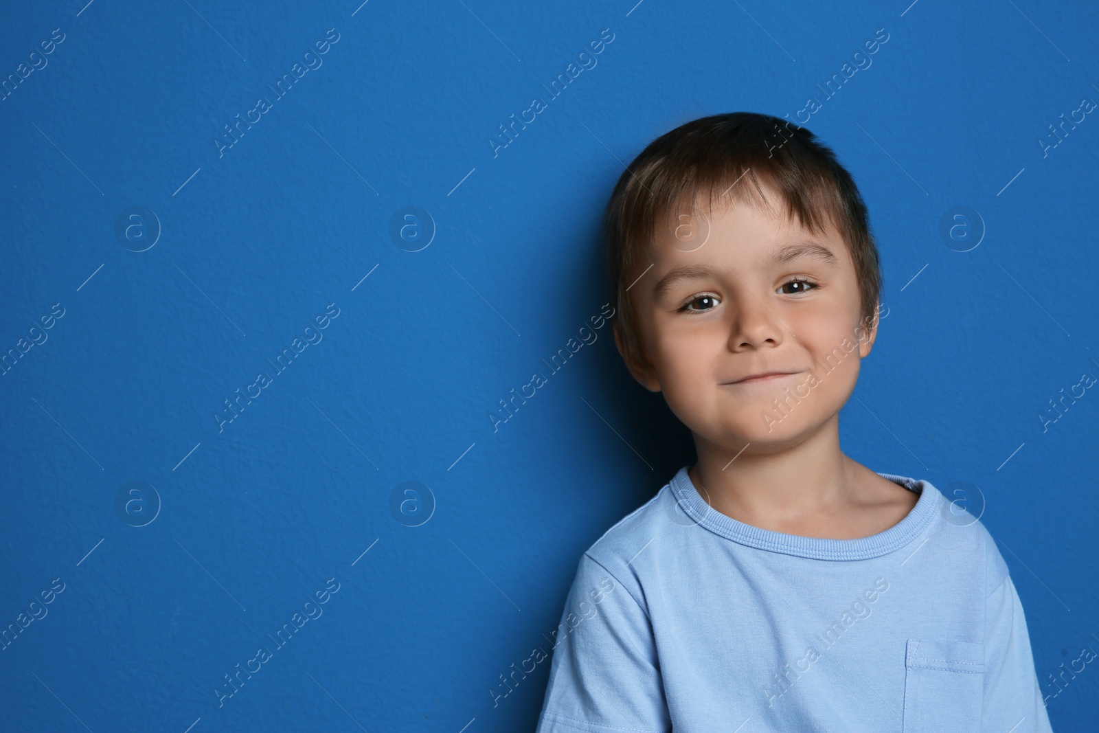Photo of Portrait of cute little boy on blue background. Space for text